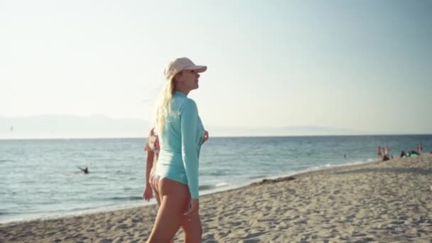 Side view of walking mom with young daughter along the sea beach on amazing tropical sunset. Pretty females walking in slow motion, sand beach in sunset, family vacations — Stock Video