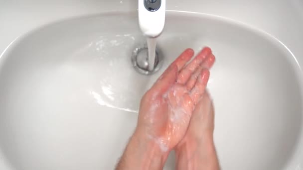 Une personne se lave les mains avec du savon moussant sous l'eau chaude qui coule dans le robinet de la salle de bain, éliminant la saleté et le virus de la peau humaine. Règles d'hygiène quotidienne pour les soins de la peau — Video