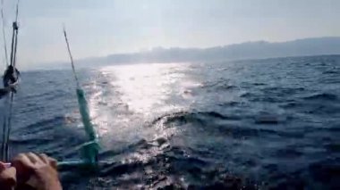 Gün batımında ekstrem uçurtma sörfü, erkek uçurtma sörfçüsü, su yüzeyinde dalgalanan su dalgalarıyla el ele tutuşuyor. Olağanüstü yaz sporu