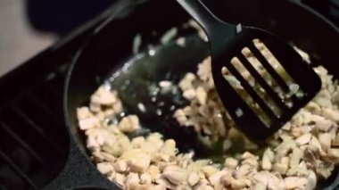 Kızartma tavasında barbekü için mantar sosu hazırlamak şampiyonları karıştırmak için kaşık kullanmak kremalı sos taze sebzeler, zeytinyağı, baharatlar ve bitkiler. bbq üzerinde sebze kızartma