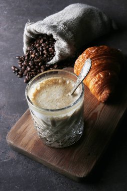 Latte, kruvasan ve keten kaplı bir poşette kahve çekirdekleri.