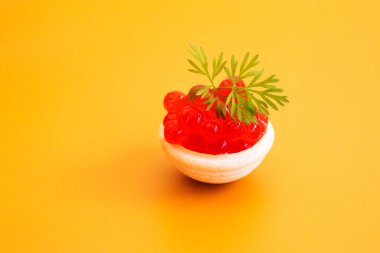 Kırmızı havyar ve yeşil filizli dereotu turtanın içinde sarı arkaplanda.