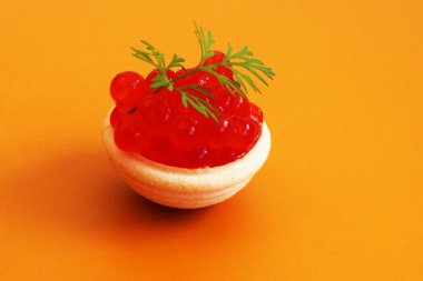 Kırmızı havyar ve yeşil filizli dereotu turtanın içinde sarı arkaplanda.