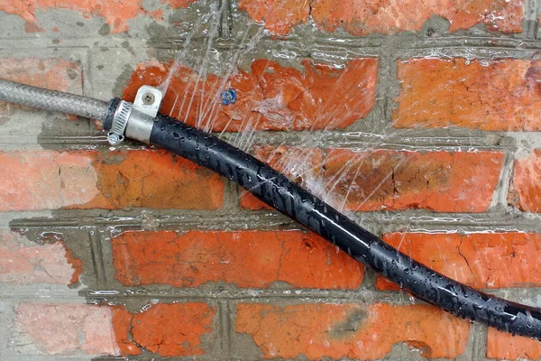 Water Flows Holes Rubber Black Hose Attached Red Brick Wall — Stock Photo, Image