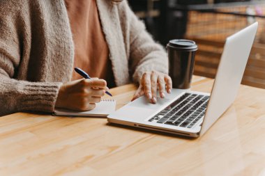 Kız bilgisayarda çalışıyor ve kahve içiyor.