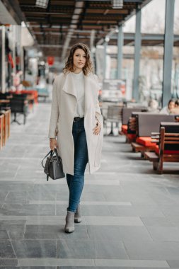 Güzel, genç, esmer bir kız şehrin restoranlarında yürüyor.