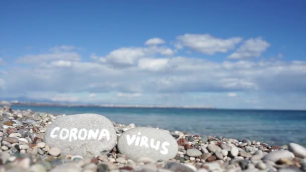 Πέτρες στην παραλία με γαλάζια θάλασσα και την επιγραφή coronavirus — Αρχείο Βίντεο