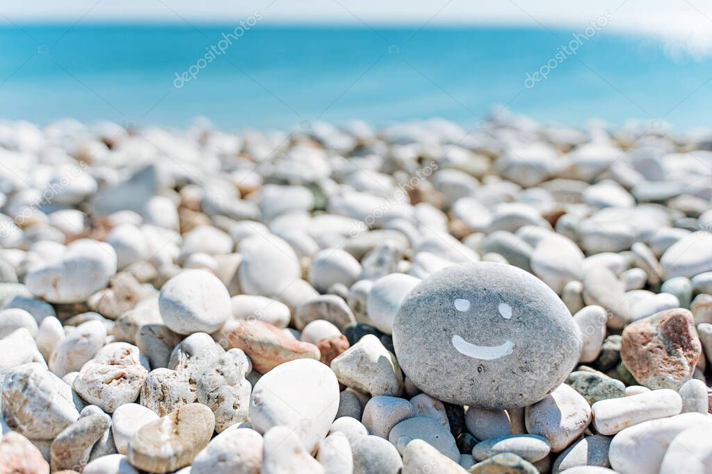 stones on the beach with a blue sea and the inscription smile