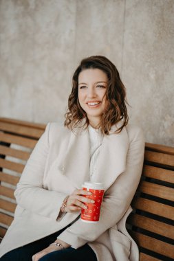 Genç ve güzel bir kız şehirde bir bankta oturuyor ve kahve ısmarlıyor.