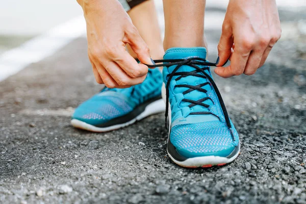 Hardlopen blauwe schoenen en runner vrouw koppelverkoop veters lopen in het bos weg. — Stockfoto
