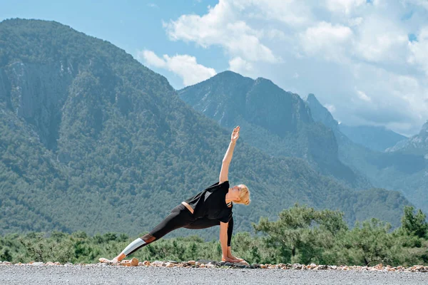 Женщина делает представления yoga снаружи и красивейший вид гор и неба с облаками — стоковое фото