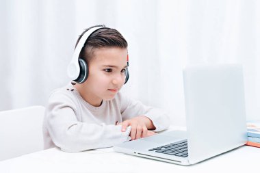  İnternette kulaklıklı bir bilgisayarın başında oturan çocuk çalışmaları. Öğretmeni dinleyen çocuk