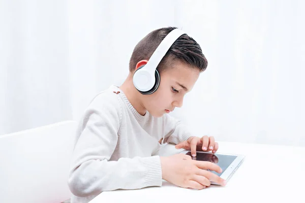 Дитяче навчання онлайн, сидячи з планшетом і навушниками. Дитина слухає вчителя і дивиться на планшет — стокове фото