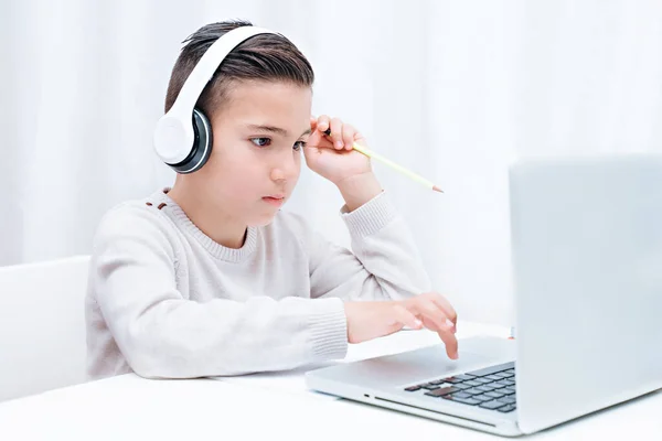 Дитяче навчання онлайн, сидячи на комп'ютері з навушниками. Дитина слухає вчителя — стокове фото