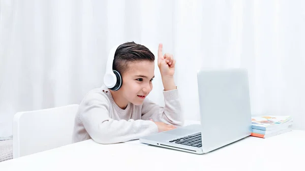 Дитяче навчання онлайн, сидячи на комп'ютері з навушниками. Дитина намагається дати відповідь — стокове фото