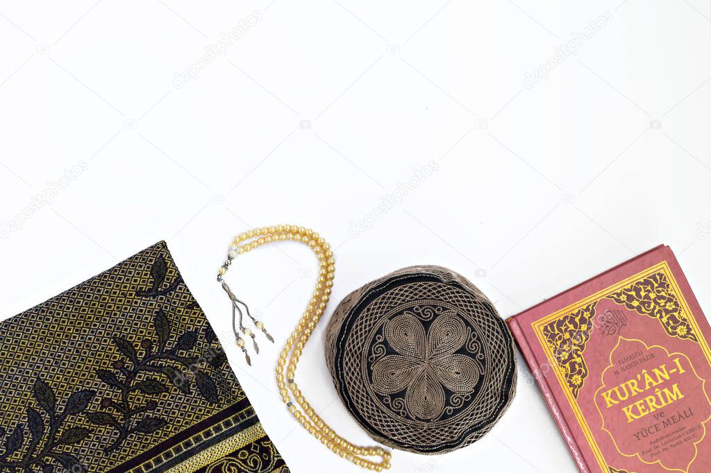  beads, koran, rug and hat for prayer or doing namaz on whine background