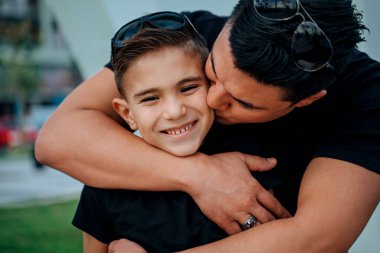 Genç bir baba oğlunu öper. Çocuk mutlu bir gülümseme.