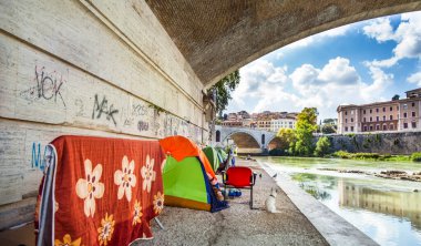 Rome Lazio Italy on October 06, 2019 Tents of homeless people under a bridge on the Tiber clipart
