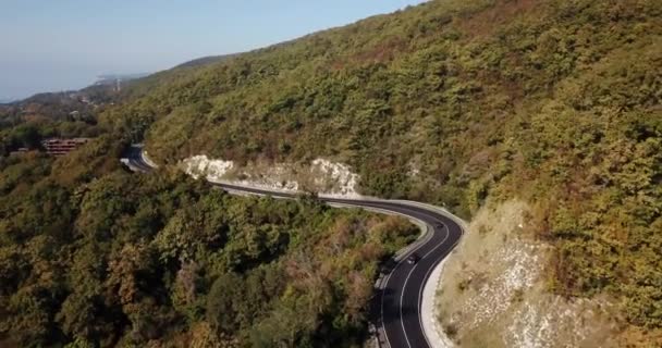 Вид с воздуха на движение автомобиля по извилистой дороге — стоковое видео