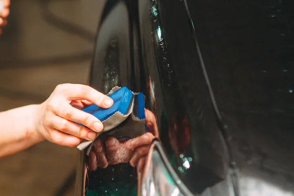 Um funcionário da lavagem de carro lava completamente realiza detalhamento — Fotografia de Stock