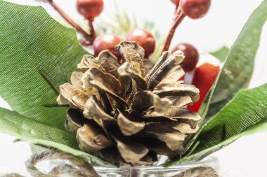 Artificial leaves, berries, natural fir cone, standing in a vase