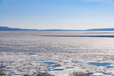 Bahar mevsiminde nehirde ince buz kütleleri, dağların ve mavi gökyüzünün arka planına karşı gün.