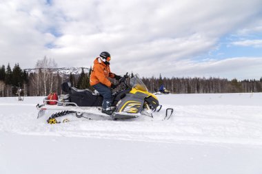 Güney Urallar 'ın dağlarındaki kış ormanlarında hareket eden bir kar aracının atleti..