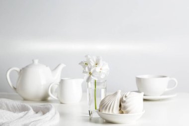 Beyaz yemekler ve hafif bir arka plan üzerinde bir vazoda çiçek.