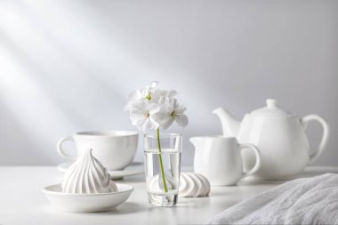 Beyaz yemekler ve hafif bir arka plan üzerinde bir vazoda çiçek.