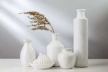 Beyaz yemekler ve hafif bir arka plan üzerinde bir vazoda çiçek.