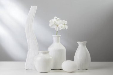 Beyaz yemekler ve hafif bir arka plan üzerinde bir vazoda çiçek.