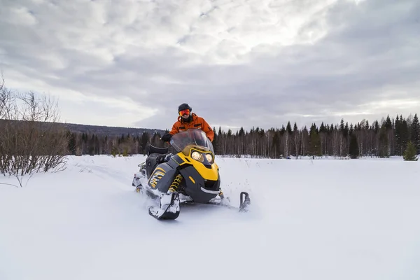 Athlete rides a snowmobile in the mountains of the Urals.