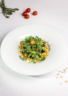 Nohut salatası, kurutulmuş domates, Brüksel lahanası ve beyaz tabakta roka..