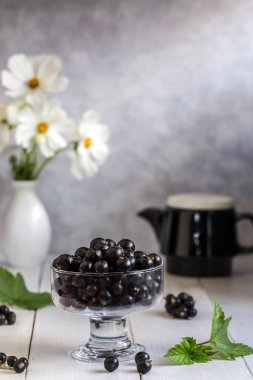 Ahşap bir masa üzerinde şeffaf bir vazo siyah frenk üzümü