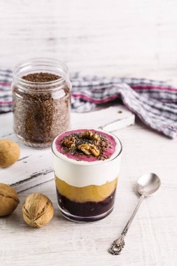 Elma soslu yoğurt, fındık ve fındık. Bardakta kaşıkla servis edilen tatlı..