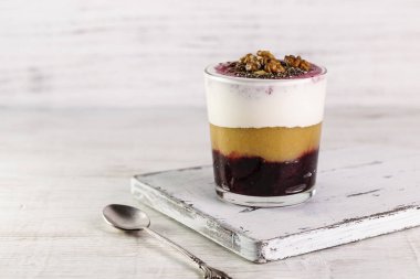 Elma soslu yoğurt, fındık ve fındık. Bardakta kaşıkla servis edilen tatlı..