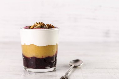 Elma soslu yoğurt, fındık ve fındık. Bardakta kaşıkla servis edilen tatlı..