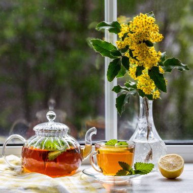 Pencere kenarındaki vazoda limon çayı ve bir buket maun..
