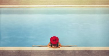 şapkalı bir genç kadın havuzda bir sicim oturur