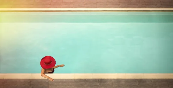 Jeune femme dans un chapeau dans la piscine au coucher du soleil — Photo