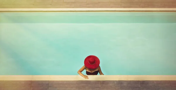 Young female in a hat  in the pool at sunset — Stock Photo, Image