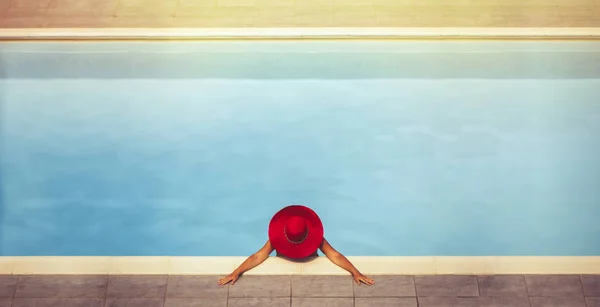 Jovem fêmea em um chapéu na piscina ao pôr do sol — Fotografia de Stock