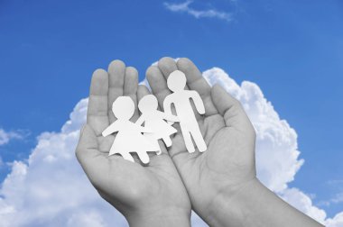 Kağıt aile içinde elleri üzerinde deniz güneşli arka plan üzerinde.