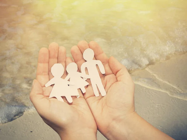 Paper Family in Hands over sea on Sunny Background.