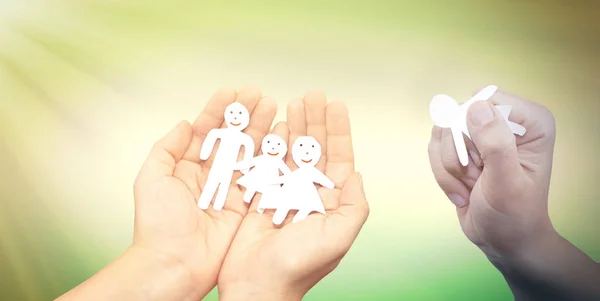 Paper Family in Hands over sea on Sunny Background.