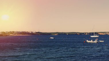 Portekizce okyanusta teknelerle günbatımında rıhtım.