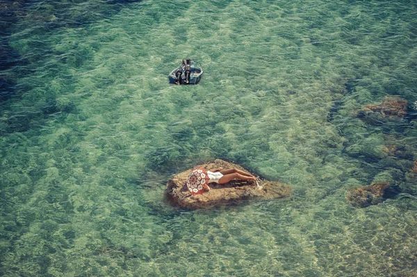 Красивая девушка на скале посреди моря с зонтиком. Вид сверху — стоковое фото