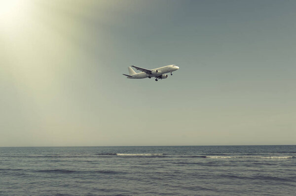 The plane landing over the sea at sunset 