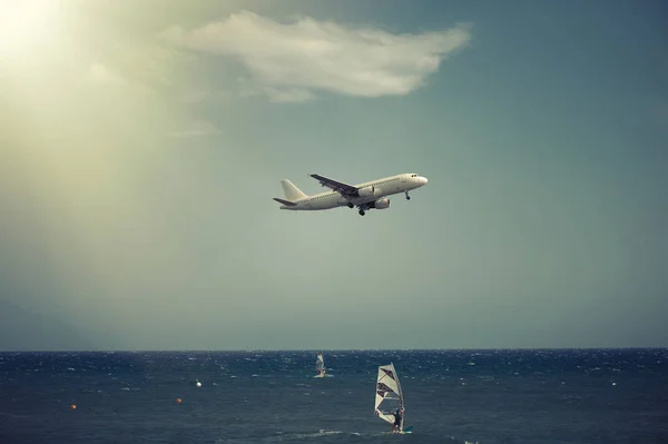 The plane landing over the sea at sunset — Stock Photo, Image