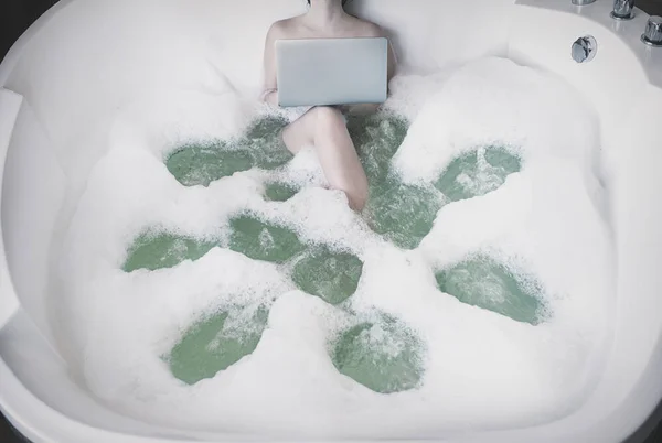 一个女孩在浴池中泡沫在电脑前工作和休息. — 图库照片